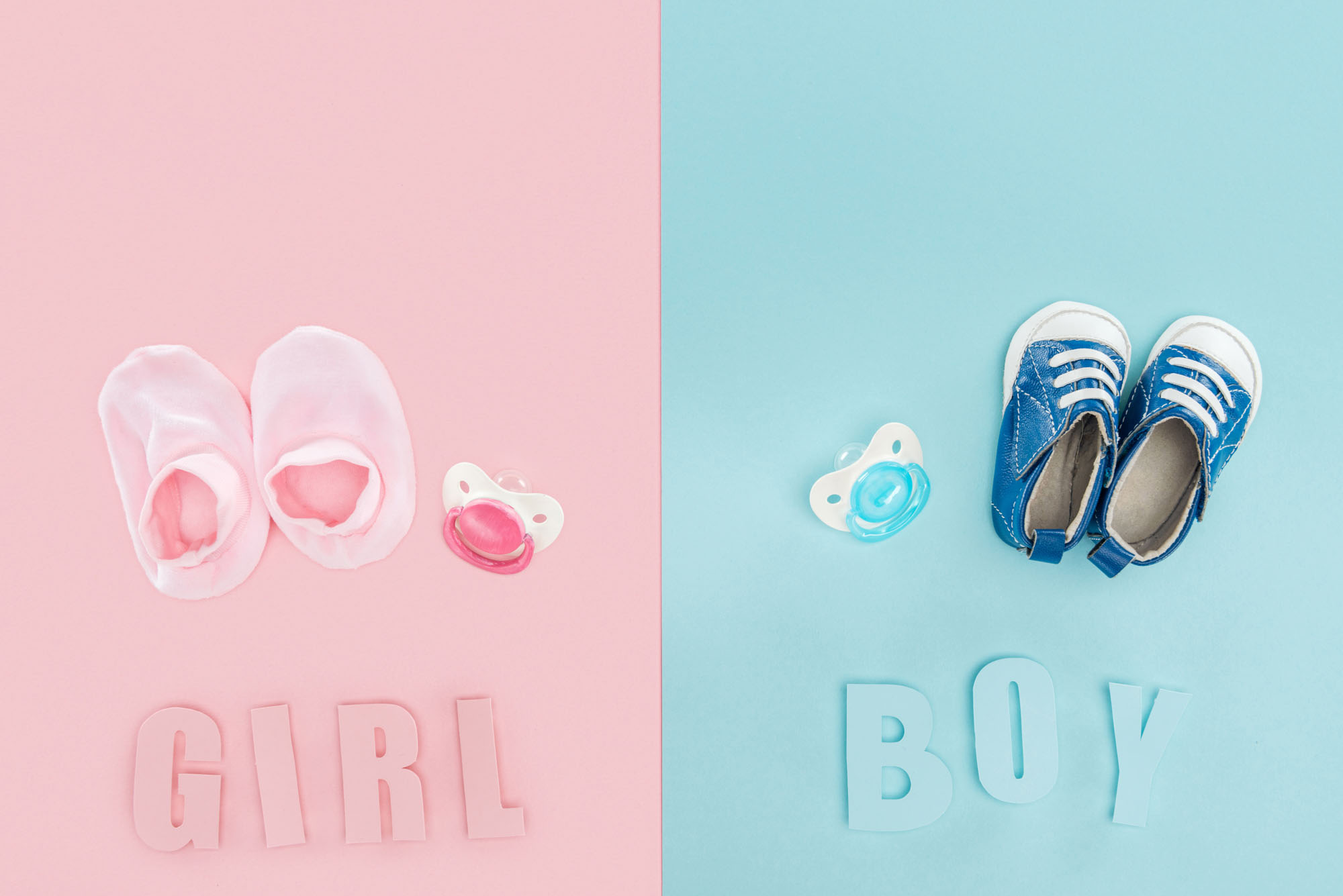 Una mitad rosa con zapatitos, chupón y letras GIRL, y una mitad azul con tenis, chupón y letras BOY.
